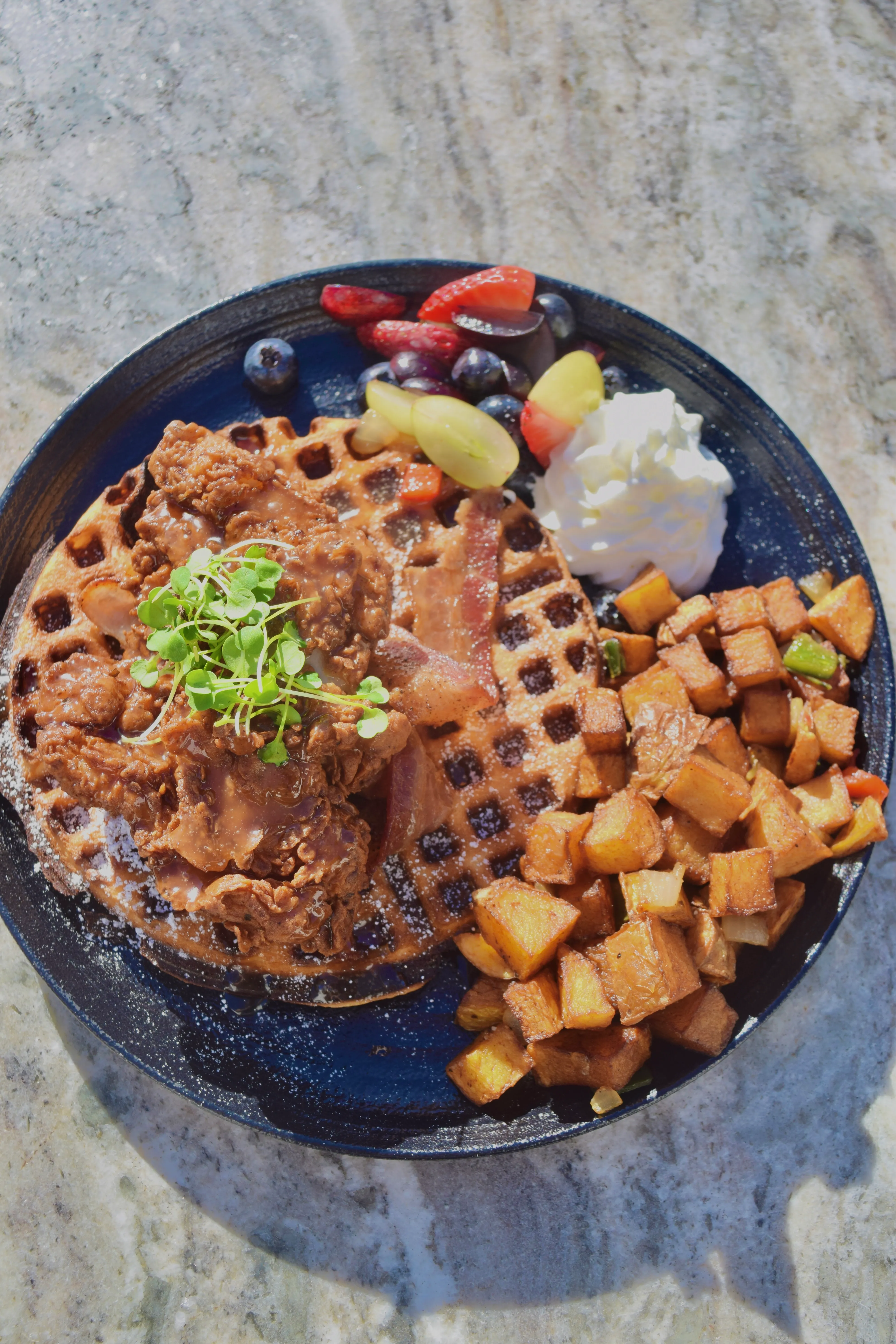 Coco Cabana chicken and waffle with hash browns, fresh fruit and whipped cream