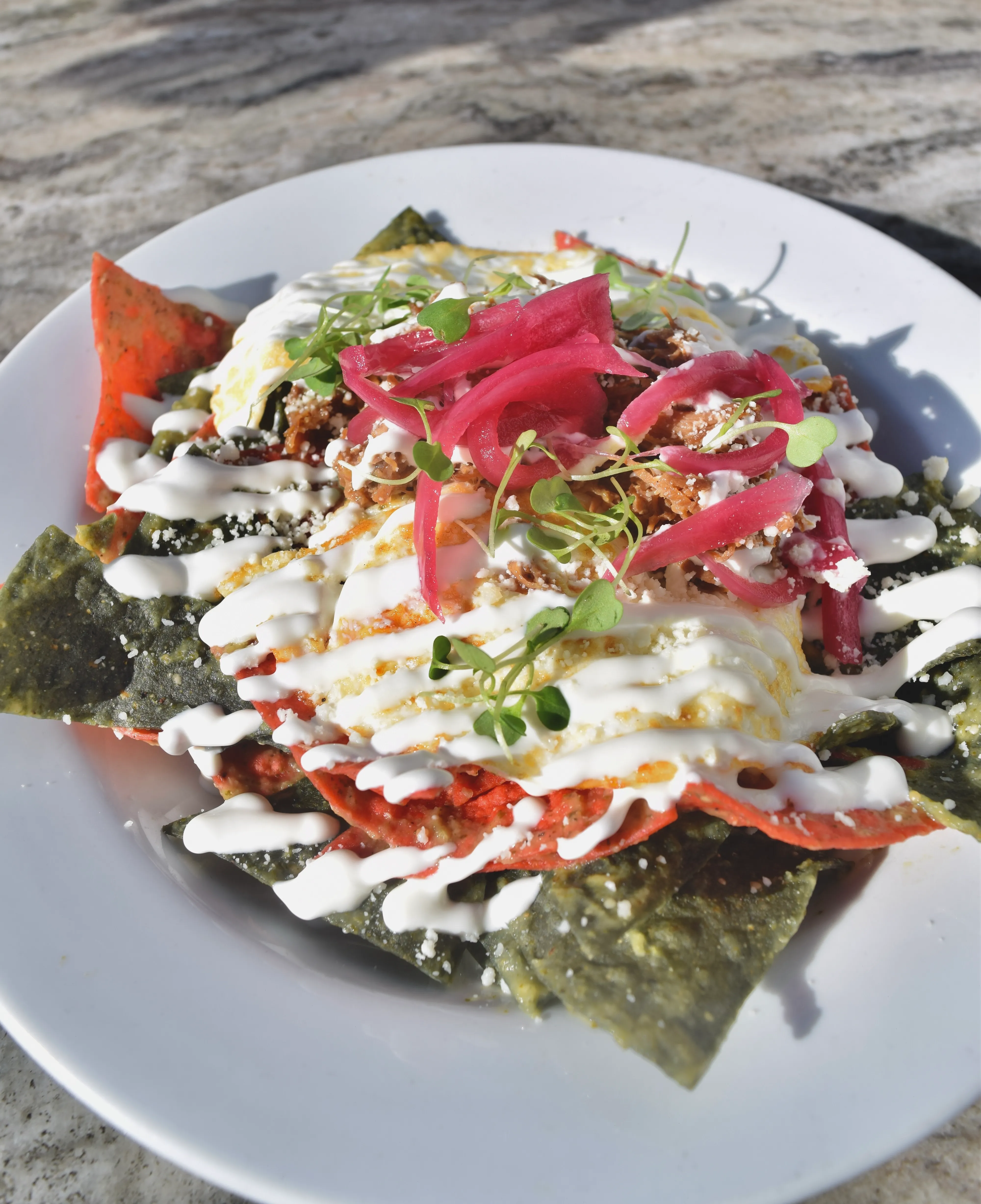 Chilaquiles with tri-color tortilla chips, crema, pickled onion and cotija