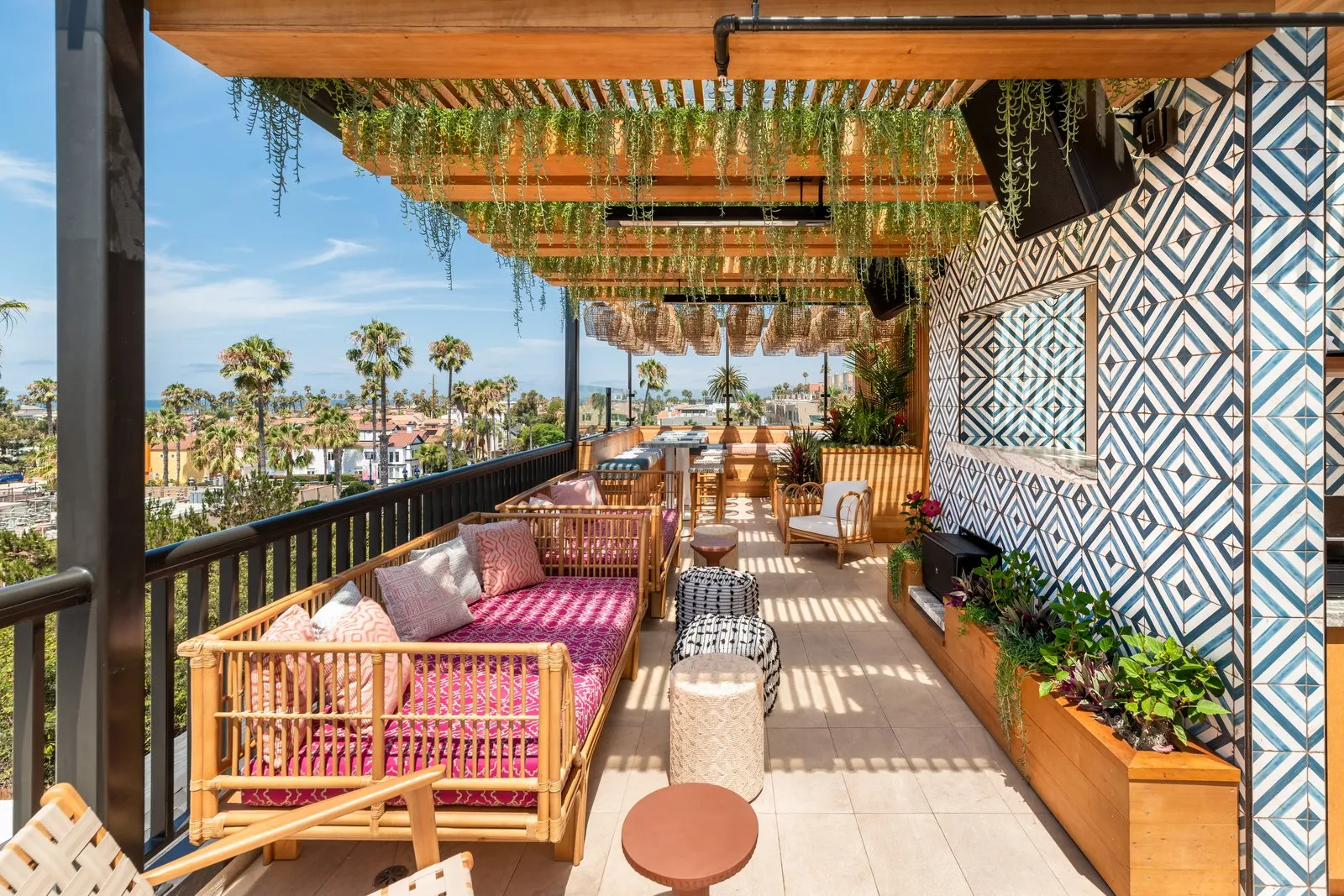 Coco Cabana lounge area with pink daybeds, geometric tile wall, and Oceanside city views